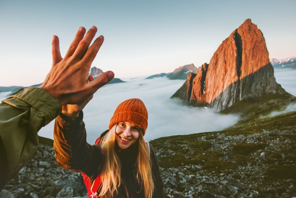 jente med oransje lue gir high five etter fjelltur